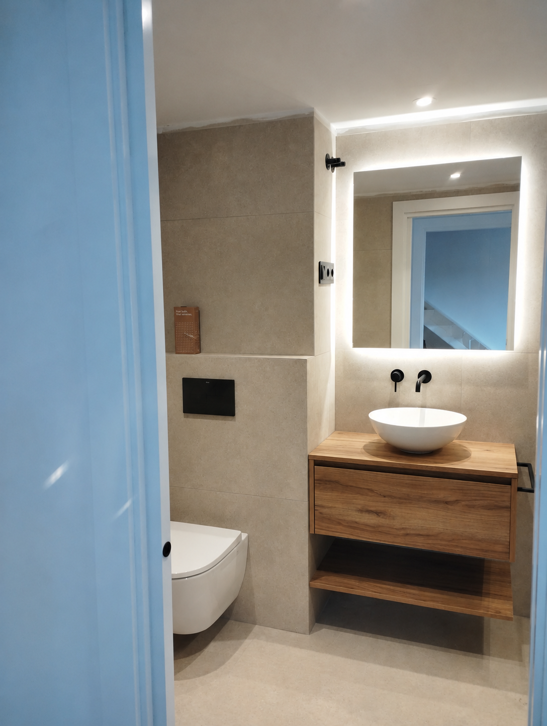 Bany modern amb mirall LED retroil·luminat i moble de fusta
