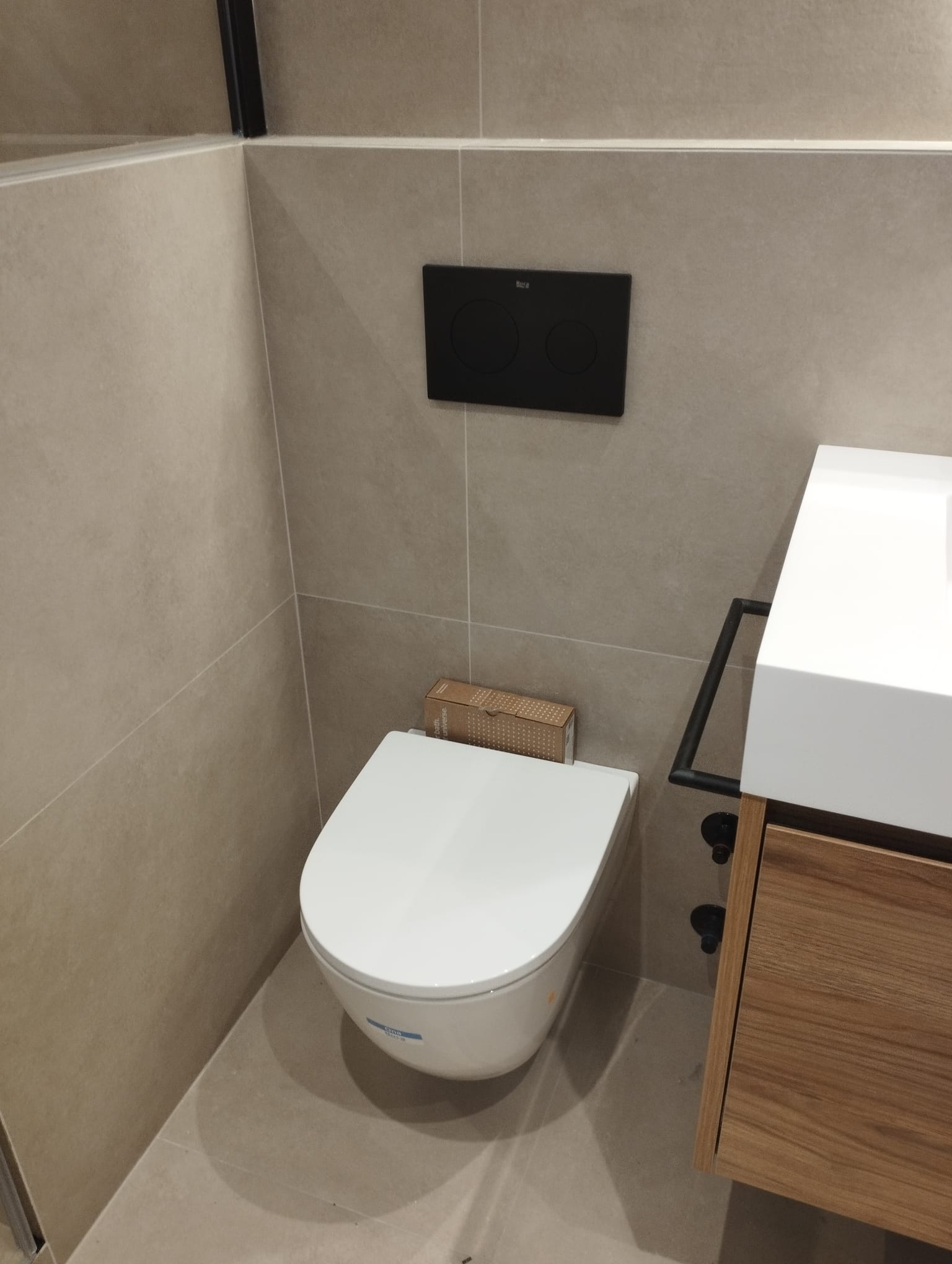 WC suspès modern ROCA amb placa de pulsació negra mat i moble de fusta