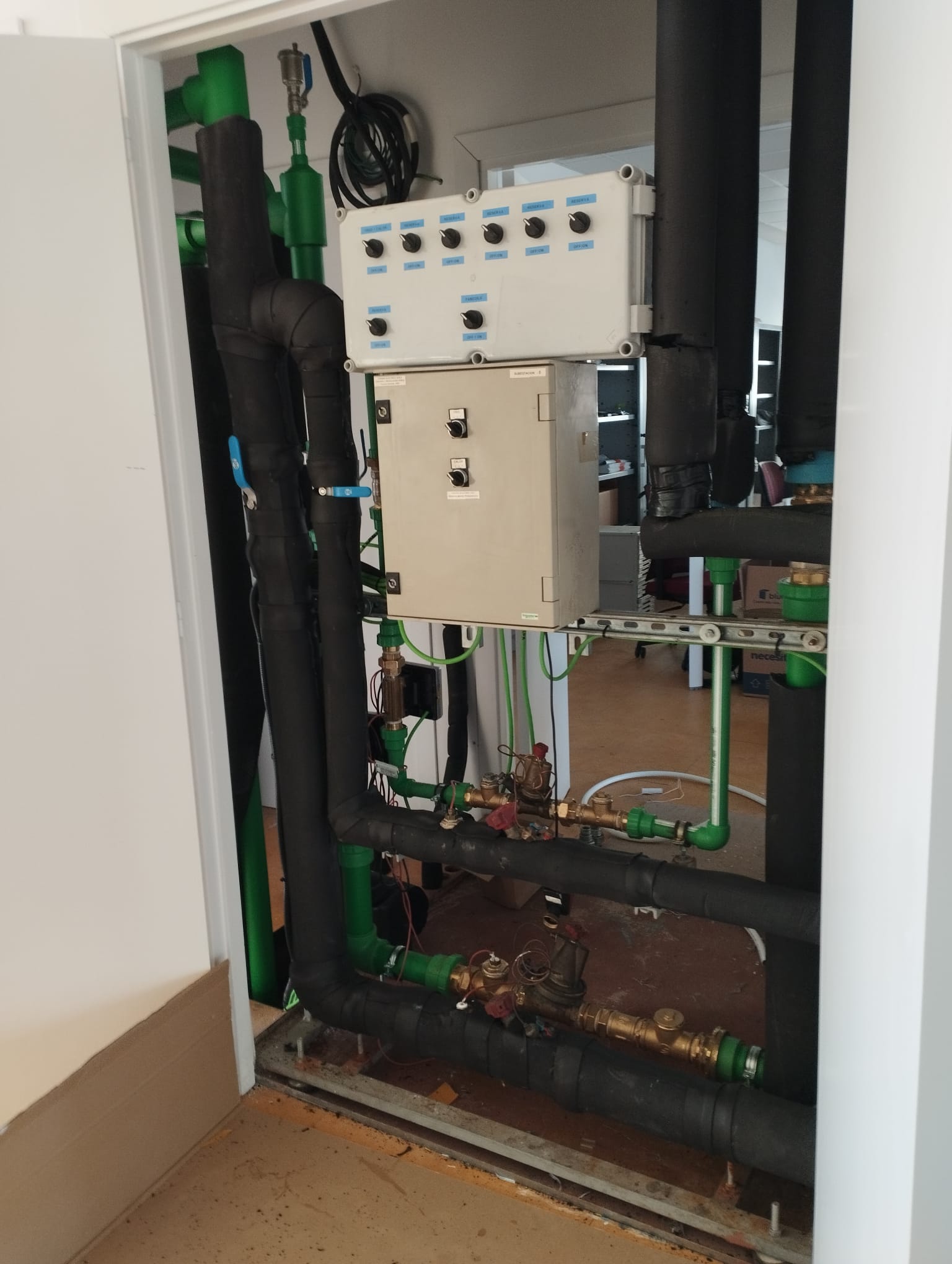 Sala d'instal·lacions amb canonades verdes aïllades i quadre de control